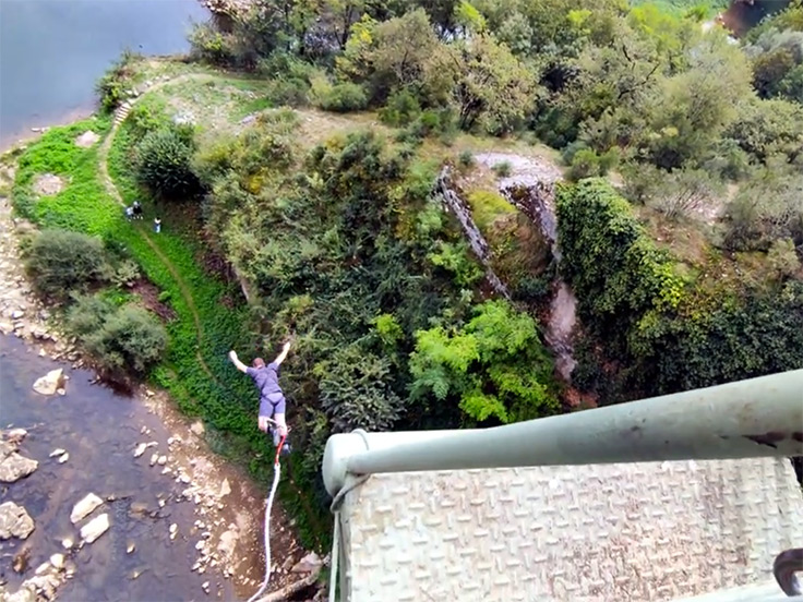 Un homme courageux saute en saut à l'élastique de la corniche de la grotte du Mas-d'Azil, proche du terrain de camping 3 étoiles avec piscine Le Petit Pyrénéen en Ariège, dans les Pyrénées