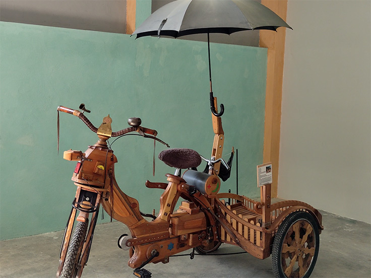 Un char moderne, tractée par une mobilette en bois, une invention étonnante de Claudius de Cap Blanc, visible à l'Affabuloscope, à côté du terrain de camping 3 étoiles avec piscine Le Petit Pyrénéen en Ariège, dans les Pyrénées