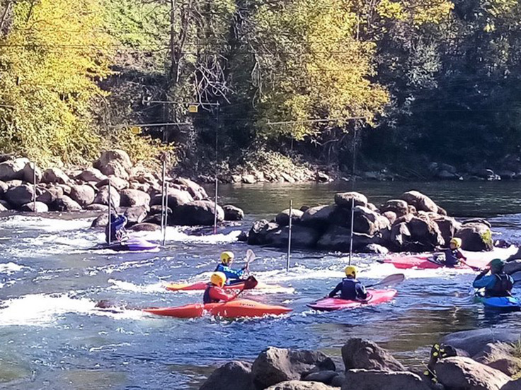 Des personnes en canoë-kayak groupées dans la rivière à la fin d'un parcours de slalom à Foix, sur l'Ariège ou l'Arget, à quelques kilomètres du camping 3 étoiles avec piscine Le Petit Pyrénéen en Ariège, dans les Pyrénées