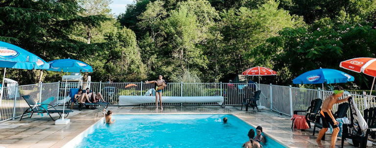 Vue de face de la piscine ensoleillée du terrain de camping 3 étoiles avec piscine Le Petit Pyrénéen en Ariège dans les Pyrénées